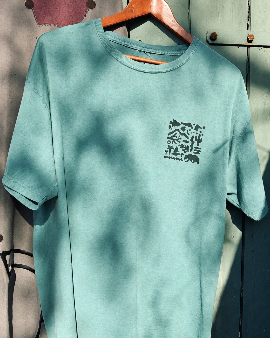 Mint graphic tee, front, hanging in dappled light